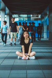 Student sitting on walkway with people walking in background