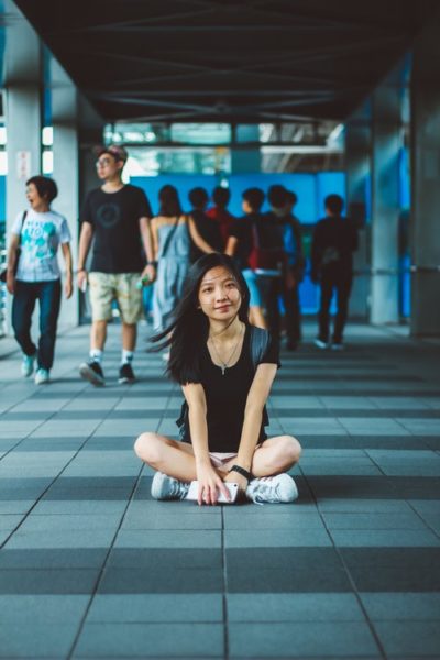 teen girl sitting cross legged on ground at a school