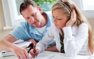 Father helping teen daughter with homework