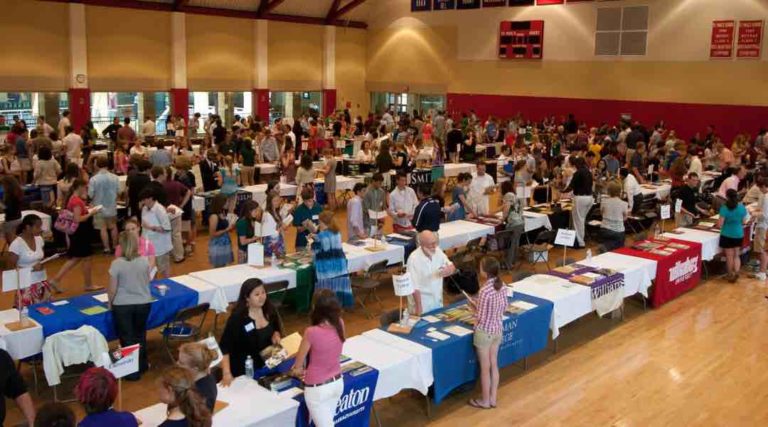 tables lined up in gym with college representatives behind them