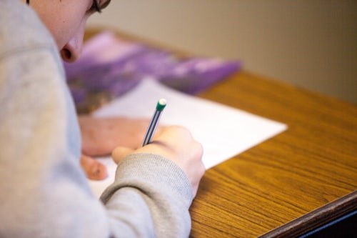 side view of student taking test at desk