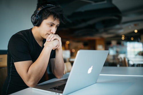 male student looking at laptop with headphones