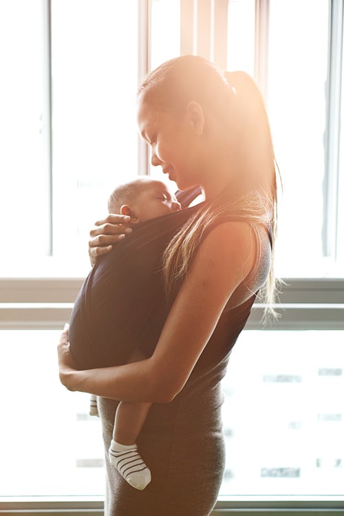 mom holding baby in front of windows