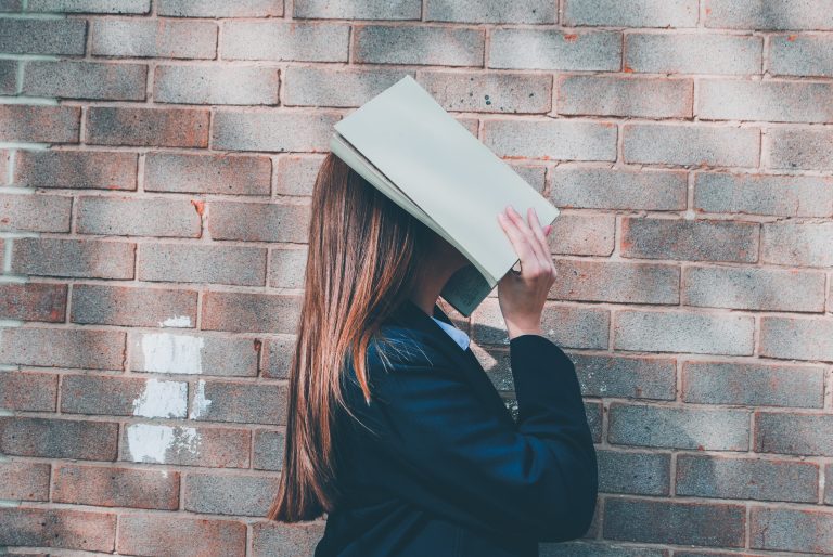 Female student covering her face with book