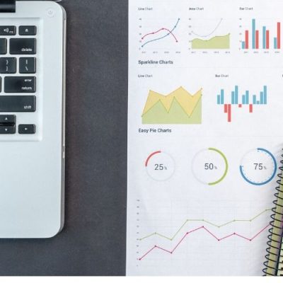 laptop with charts on table next to it