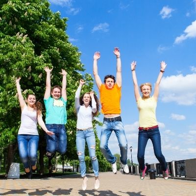 Five teenagers jumping with arms in the air