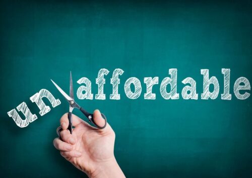 The word "unaffordable" on a chalkboard, with the "un" prefix being snipped off by scissors