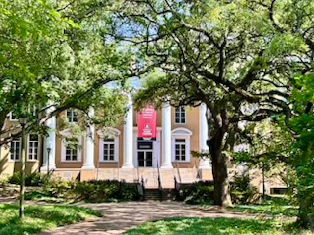 building with columns and banner at university of south carolina surrounded by trees